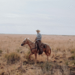 Cowboy reitet über einen Feldweg